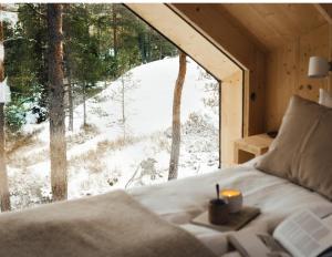 sypialnia z łóżkiem i dużym oknem ze śniegiem w obiekcie Hilltop Forest w mieście Inkoo