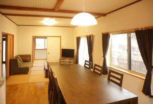 Active House Ryuo - Vacation STAY 04019v في Shimotakai: غرفة معيشة مع طاولة خشبية كبيرة مع كراسي
