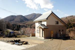 a small white house with mountains in the background at Active House Ryuo - Vacation STAY 04019v in Shimotakai