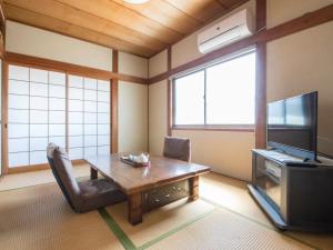 a living room with a table and a tv at Minpaku Yamamoto - Vacation STAY 13868 in Izumiotsu