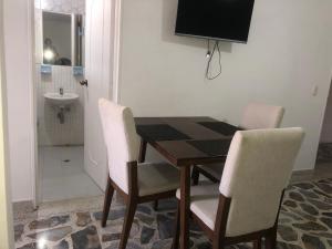 mesa de comedor con sillas blancas y TV en Apartamento cómodo , céntrico y bien ubicado Apto 301, en Medellín