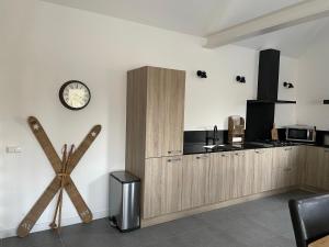 een keuken met houten kasten en een klok aan de muur bij Gastenverblijf bij de Buuren in Dirksland
