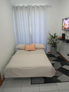 um quarto com uma cama grande e lençóis brancos em Apartamento ao lado da Vila Germânica em Blumenau