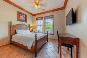 Schlafzimmer mit einem Bett, einem Schreibtisch und einem TV in der Unterkunft Grand Colony Island Villas in San Pedro