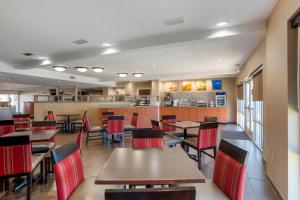 un restaurante con mesas de madera y sillas rojas en Comfort Suites Foley - North Gulf Shores en Foley