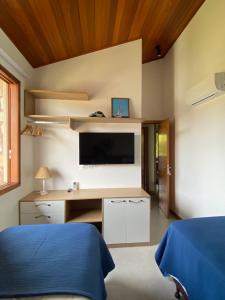 a bedroom with a bed and a desk with a television at Flat Alto Padrão Barra Grande in Barra Grande