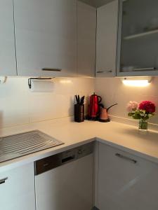 una cocina con armarios blancos y un jarrón de flores en Your home in istanbul, en Estambul