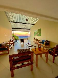 a living room with wooden tables and a view of the ocean at Pousada O Canto do Jacu in Martins