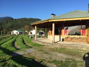 a farm with a building and a grass field at Los Coihues Patagonia Lodge in La Junta