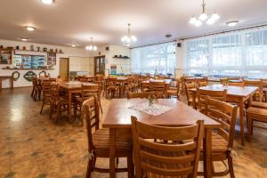 un restaurante con mesas y sillas de madera y ventanas en Liščí Mlýn, en Frenštát pod Radhoštěm