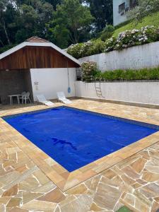 una gran piscina azul con suelo de madera en Apartamento em Condomínio Campos do Jordão, en Campos do Jordão