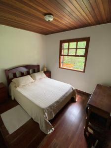 Un dormitorio con una cama grande y una ventana en Apartamento em Condomínio Campos do Jordão, en Campos do Jordão