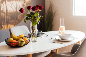 a white table with a vase of flowers and a bowl of fruit at Stay at Smilla - Boutique Apartments mit Küche - Parken - Klima - Netflix - Waschmaschine in Wiesbaden