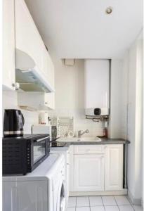 a white kitchen with a microwave and a dishwasher at SUITE ELISE Passy in Paris