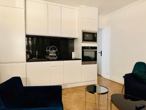 a kitchen with white cabinets and black appliances at Home Sweet Home Champs de Mars in Paris