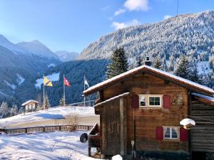 uma cabana de madeira na neve com montanhas ao fundo em Sonniges Chalet Arosa für 6 Pers alleinstehend mit traumhaftem Bergpanorama em Langwies