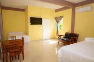 a room with two beds and a table and a tv at La Cascada Stays in San Ignacio