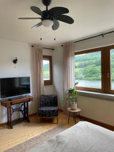 a bedroom with a ceiling fan and a television at Boutique Guesthouse Das WOHLGEMUTH HEIM Mosel Weingut in Zell an der Mosel