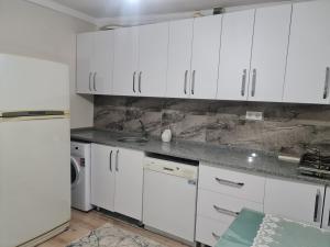 cocina con armarios blancos y nevera blanca en Bahçeli büyük köy evi, en Fethiye