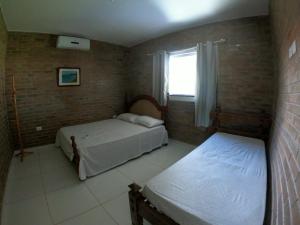 a bedroom with two beds and a window at Solar Leão Beach in Luis Correia