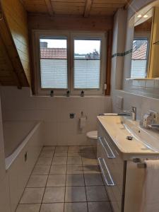 a bathroom with two sinks and a tub and a toilet at Ferienwohnung am Schönberg - Ebringen in Ebringen