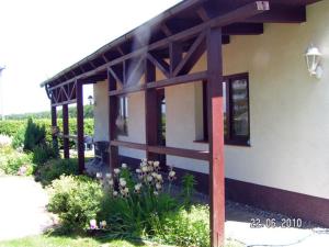 a house with a wooden roof with flowers in front of it at Apartment Tina in Ahrenshagen