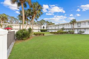 a large yard in front of a building with palm trees at Baymont by Wyndham Jacksonville Airport in Jacksonville