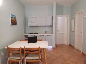 - une cuisine avec une table, des chaises et un ordinateur portable dans l'établissement Villetta Trilocale con Giardino 1.3, à Porto Pollo
