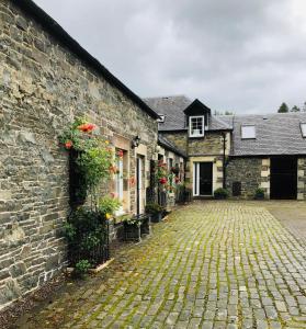 a cobblestone street in front of a stone building at Glenheurie Cottage in Polmood