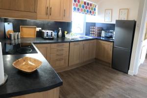 a kitchen with wooden cabinets and a black refrigerator at Glenheurie Cottage in Polmood