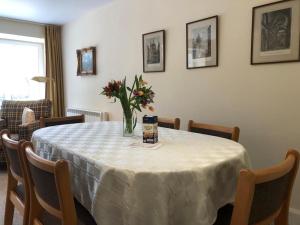 una mesa con un jarrón de flores. en Glenheurie Cottage en Polmood