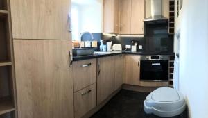 uma pequena cozinha com armários de madeira e um lavatório em Lategillan Cottage em Polmood