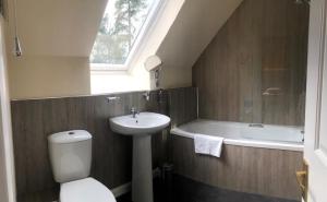 a bathroom with a sink and a toilet and a bath tub at Lategillan Cottage in Polmood