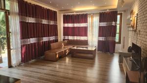 a living room with a leather couch in front of windows at Venus Resort & Coffee House in Bāndarban