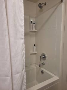 a white bathroom with a shower with a shower curtain at Downtown SLC Apt w/amenities in Salt Lake City