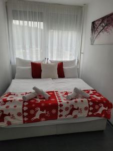 a bed with a red and white blanket and a window at Krisztina Apartman in Salgótarján