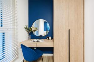 a dressing table with a blue chair and a mirror at Pearl Apartment by LoftAffair in Gdańsk