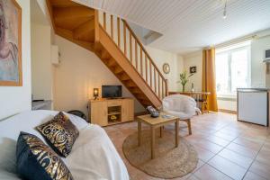 a living room with a staircase with a couch and a table at Gîtes Le Bois Berranger in Saint-Urbain