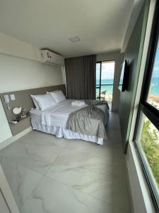 a bedroom with a bed and a view of the ocean at Flat à Beira Mar Com Varanda e Piscinas Naturais in Ipojuca