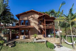 a brick house with a porch and palm trees at Temporada Retiro do Chalé Brumadinho MG in Brumadinho