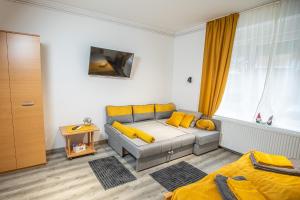 ein Wohnzimmer mit Sofa und gelben Kissen in der Unterkunft Cent-room apartman Ada in Ada