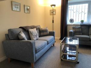 sala de estar con sofá y mesa en Manyleith Rig Cottage en Polmood