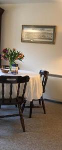 una mesa con un jarrón de flores y una silla en Manyleith Rig Cottage en Polmood