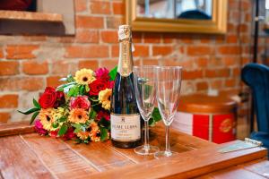a bottle of wine and glasses on a table with flowers at Loft nad Szpularnią in Żyrardów