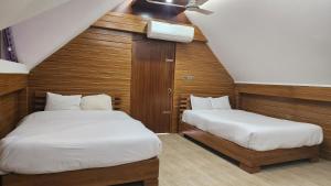 two beds in a small room with wooden walls at Venus Resort & Coffee House in Bāndarban