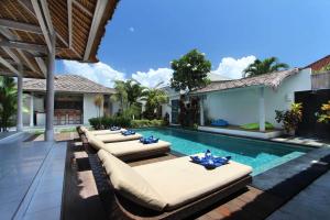 uma piscina com espreguiçadeiras e cadeiras ao lado de uma casa em Villa Noa by Optimum Bali Villas em Seminyak