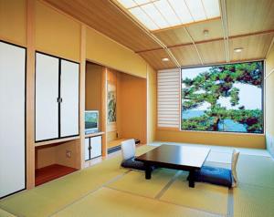 uma sala de jantar com mesa, cadeiras e janelas em Oishiya em Ise