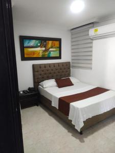 1 dormitorio con 1 cama y una pintura en la pared en Hotel Suite Imperial 72, en Barranquilla
