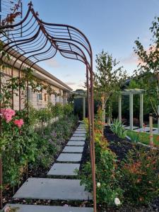 a garden with an arbor and a walkway at Omokoroa Golfers Retreat - B&B in Omokoroa