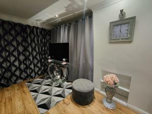 a living room with a stool and a clock on the wall at GRAVESEND - BEAUTIFUL Studio in Kent